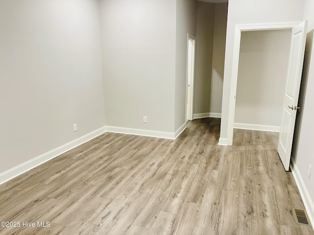 unfurnished room featuring light wood-type flooring, visible vents, and baseboards