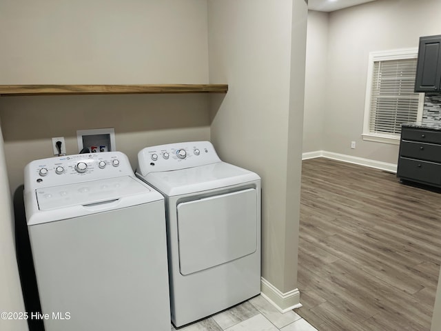 clothes washing area featuring light wood-style floors, washing machine and dryer, laundry area, and baseboards