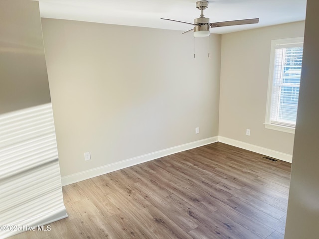 unfurnished room with light wood finished floors, a ceiling fan, visible vents, and baseboards