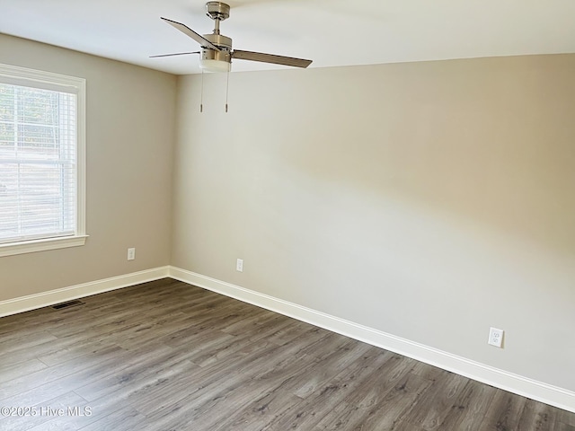 spare room with baseboards, visible vents, and wood finished floors