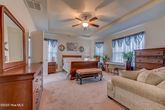 bedroom featuring light carpet, ceiling fan, a raised ceiling, and visible vents