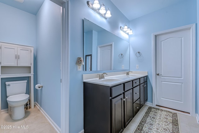 full bath with double vanity, toilet, a sink, and tile patterned floors