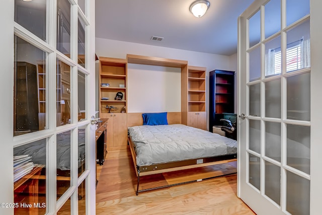 bedroom with light wood-style floors, visible vents, and french doors