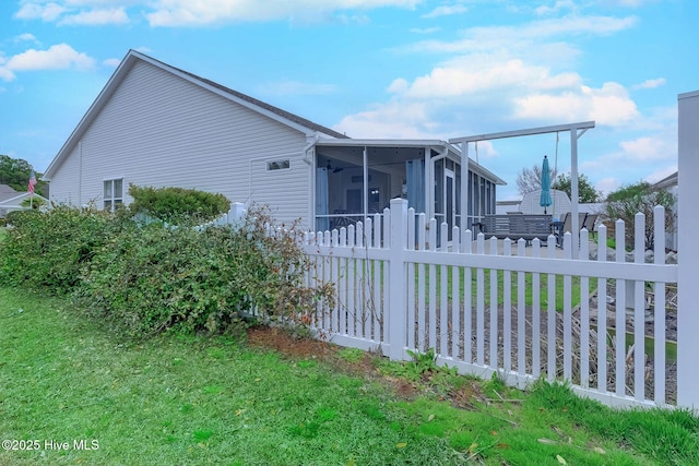 view of side of property featuring a lawn, fence, and a sunroom