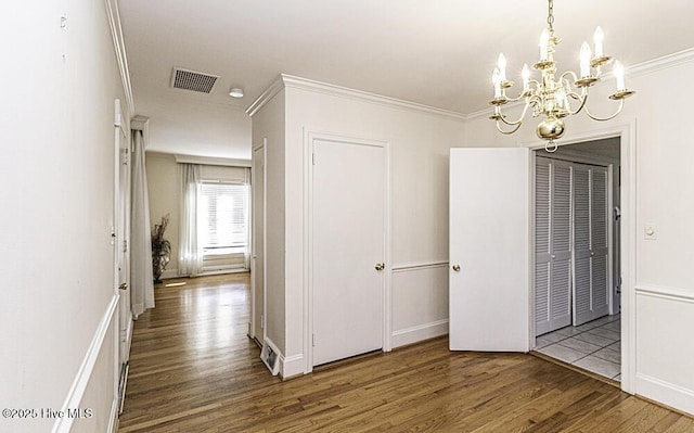 corridor with crown molding, visible vents, a chandelier, and wood finished floors