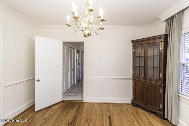 unfurnished dining area featuring light wood-style floors, baseboards, and ornamental molding