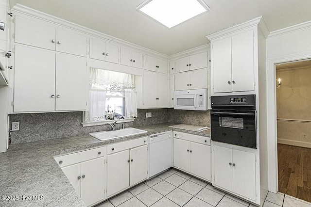 kitchen featuring crown molding, light countertops, white cabinets, a sink, and white appliances