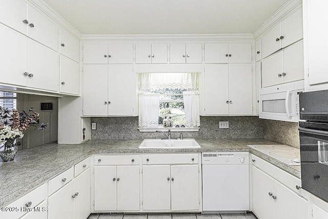 kitchen with white appliances, a sink, white cabinets, light countertops, and decorative backsplash