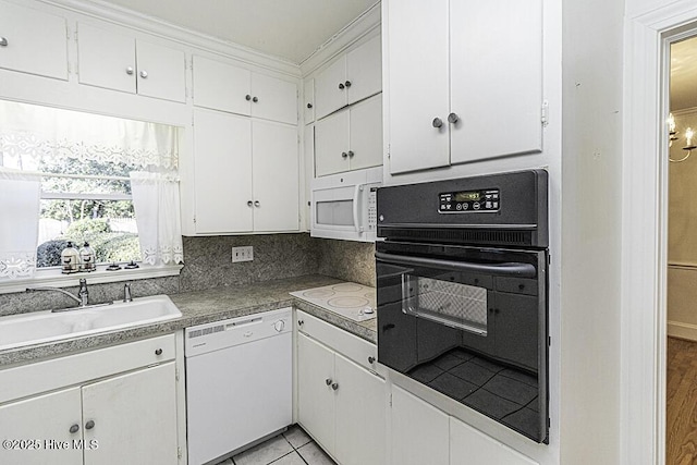 kitchen featuring tasteful backsplash, dark countertops, white cabinets, a sink, and white appliances