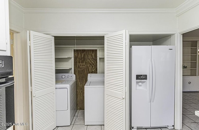 clothes washing area featuring laundry area, washing machine and dryer, ornamental molding, and light tile patterned flooring