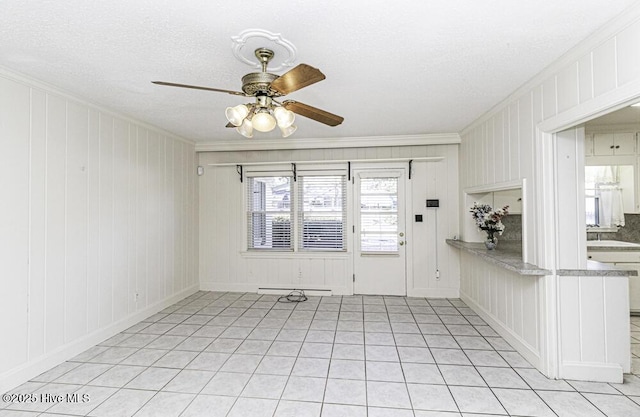 spare room with ceiling fan, a textured ceiling, a baseboard heating unit, and crown molding