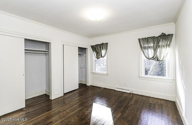 unfurnished bedroom with baseboards, visible vents, ornamental molding, dark wood-type flooring, and multiple closets