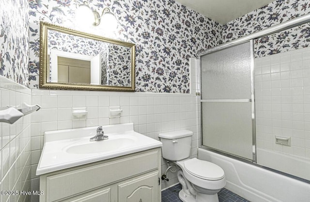 full bathroom featuring wallpapered walls, wainscoting, toilet, enclosed tub / shower combo, and tile patterned flooring