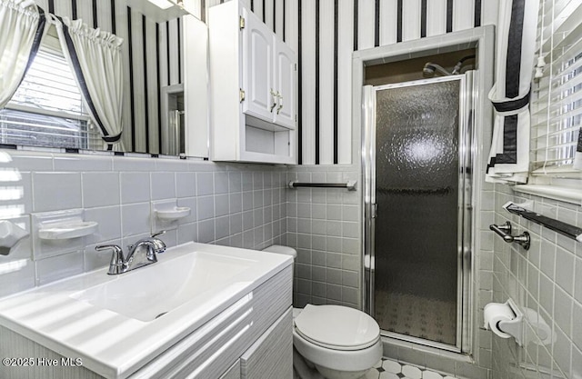 bathroom with a stall shower, tile walls, vanity, and toilet