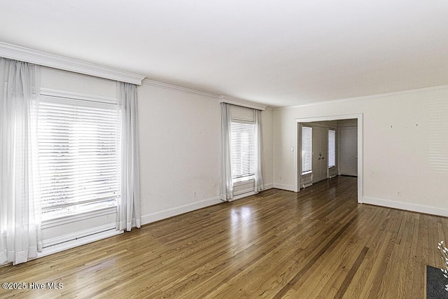 spare room with dark wood-style floors, crown molding, and baseboards