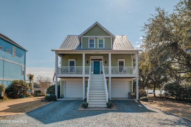 raised beach house with covered porch, stairway, an attached garage, metal roof, and driveway