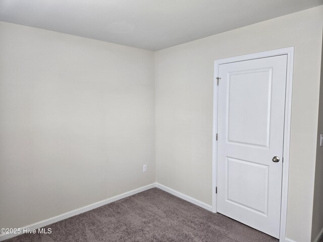 hallway featuring baseboards and dark carpet