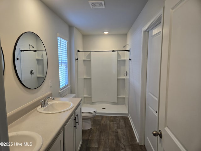 full bath featuring visible vents, a sink, toilet, and wood finished floors