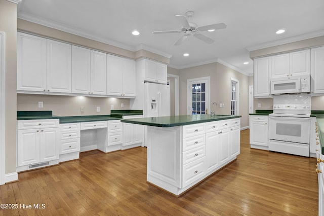 kitchen featuring dark countertops, white appliances, and white cabinetry