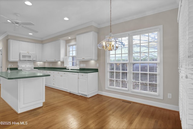 kitchen with pendant lighting, light wood finished floors, dark countertops, white cabinetry, and white appliances