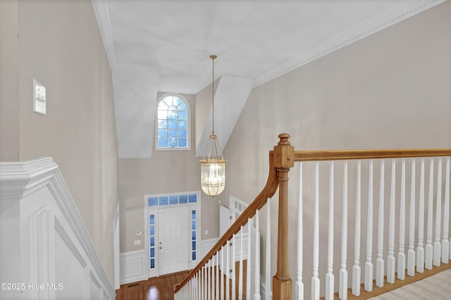 foyer entrance featuring ornamental molding, wainscoting, and an inviting chandelier