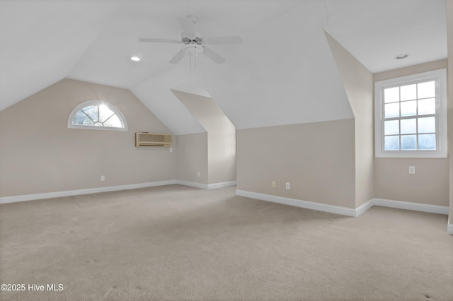 bonus room with baseboards, a ceiling fan, light colored carpet, a wall mounted air conditioner, and vaulted ceiling