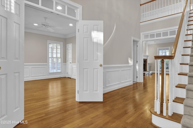 foyer entrance featuring stairs, ornamental molding, a wealth of natural light, and a ceiling fan