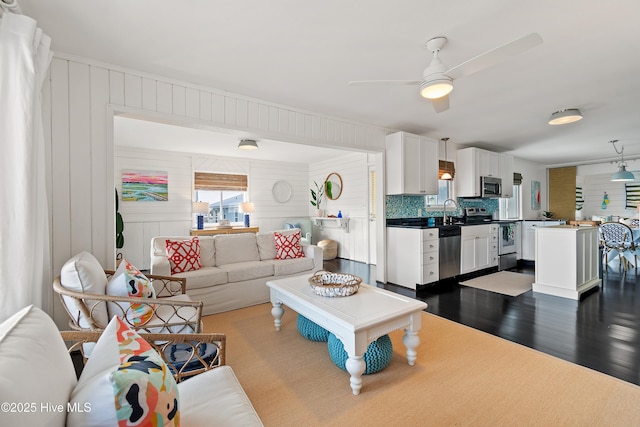 living area featuring ceiling fan and dark wood-type flooring