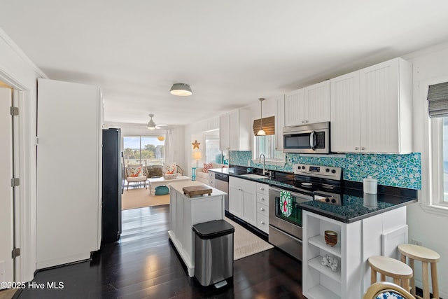 kitchen featuring white cabinets, appliances with stainless steel finishes, hanging light fixtures, open shelves, and a sink