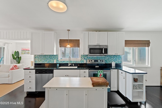 kitchen with a sink, white cabinets, appliances with stainless steel finishes, open shelves, and pendant lighting