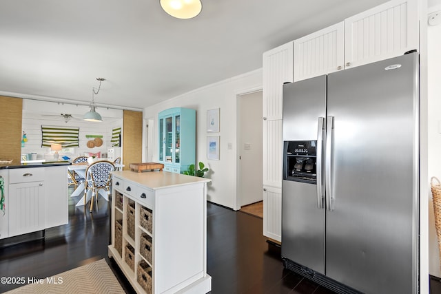 kitchen featuring stainless steel fridge with ice dispenser, a kitchen island, dark wood-style flooring, decorative light fixtures, and white cabinetry