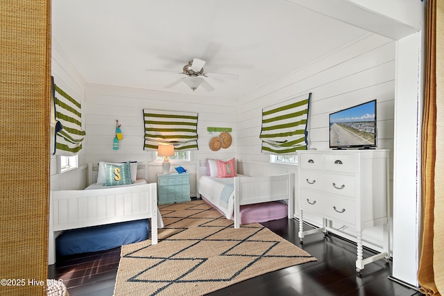 bedroom featuring ceiling fan, multiple windows, and wood finished floors