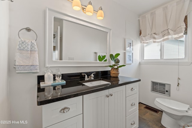 bathroom featuring stone finish floor, visible vents, vanity, and toilet