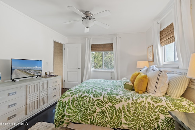 bedroom with ornamental molding, multiple windows, ceiling fan, and wood finished floors