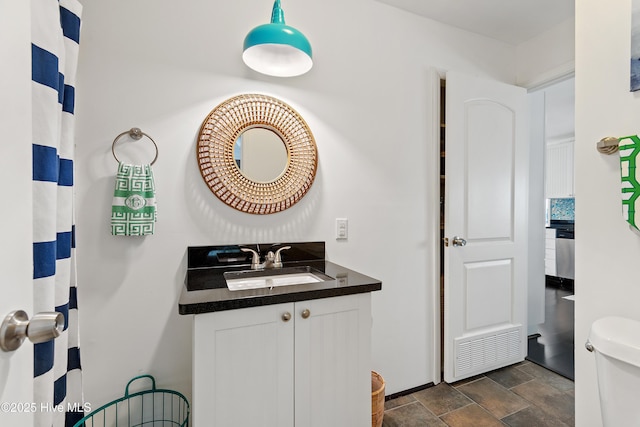 full bathroom featuring stone finish flooring, vanity, and toilet