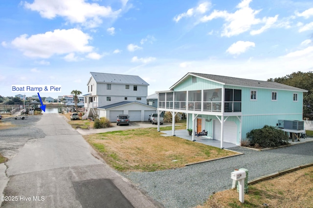 view of front facade with a garage, a front yard, a sunroom, and central air condition unit