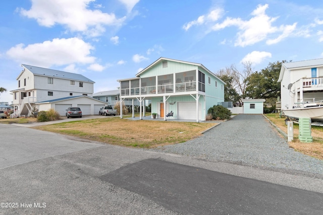 view of front facade with a garage, a sunroom, driveway, a residential view, and a front lawn