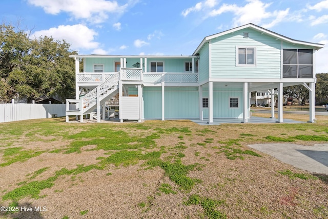 rear view of house featuring stairs, fence, a yard, a porch, and a carport