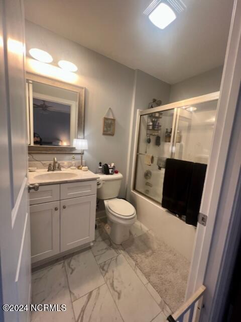 full bath featuring toilet, marble finish floor, shower / bath combination with glass door, and vanity