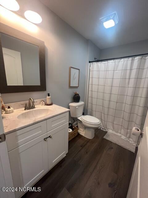 full bath with a shower with shower curtain, vanity, toilet, and wood finished floors