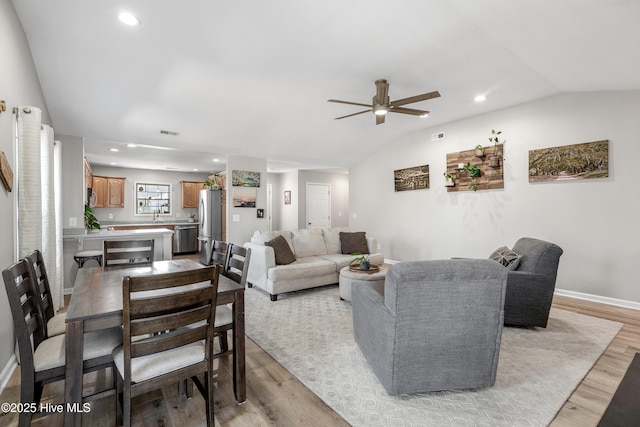 living area featuring lofted ceiling, baseboards, light wood finished floors, and recessed lighting