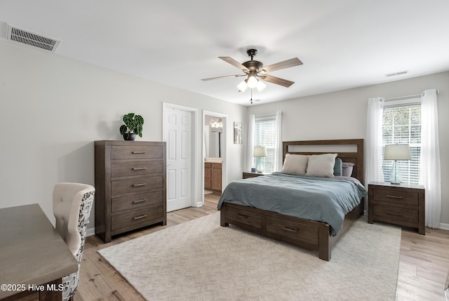 bedroom with light wood finished floors, visible vents, a ceiling fan, and ensuite bathroom