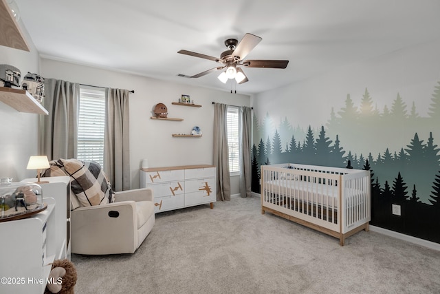 bedroom featuring a nursery area, ceiling fan, baseboards, and carpet flooring