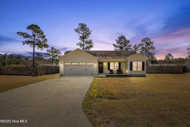 view of front facade with concrete driveway, a yard, and fence