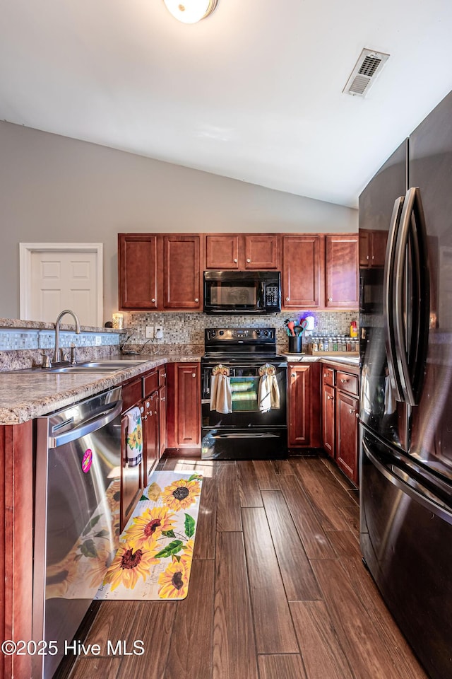 kitchen with tasteful backsplash, visible vents, vaulted ceiling, black appliances, and a sink