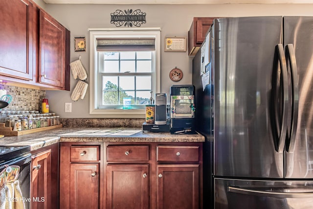 kitchen featuring backsplash, freestanding refrigerator, and reddish brown cabinets