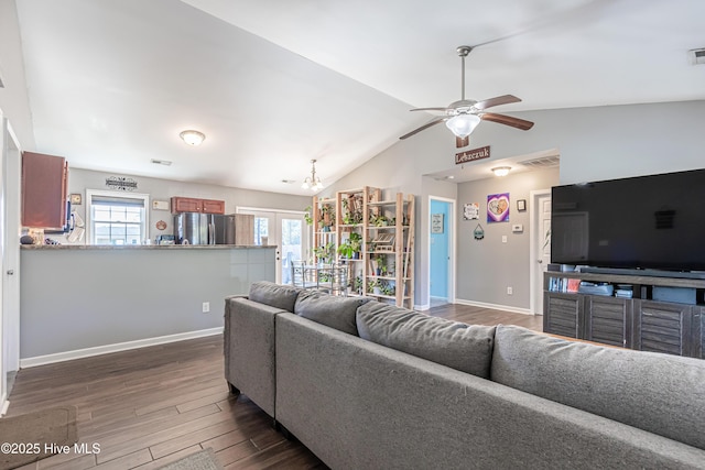 living area featuring baseboards, vaulted ceiling, dark wood-style flooring, and ceiling fan with notable chandelier