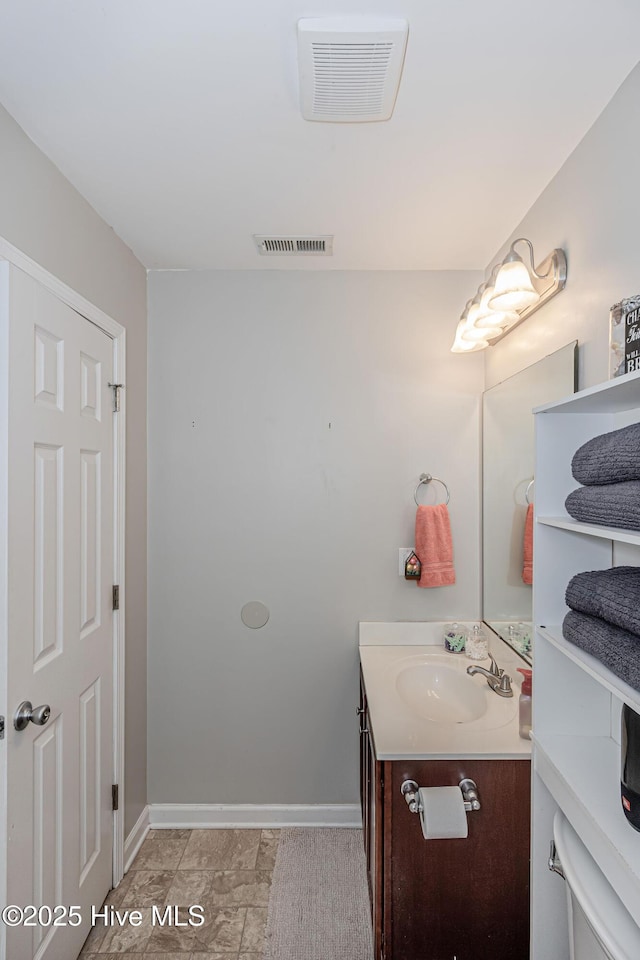 bathroom featuring visible vents, baseboards, and vanity