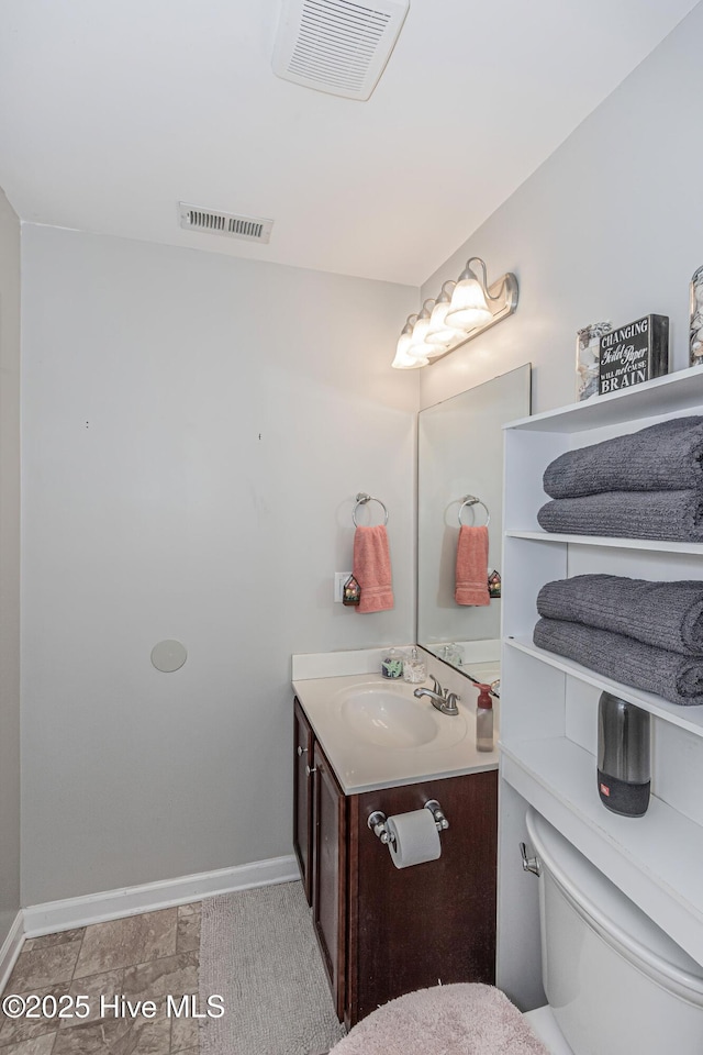 bathroom with visible vents, baseboards, toilet, and vanity