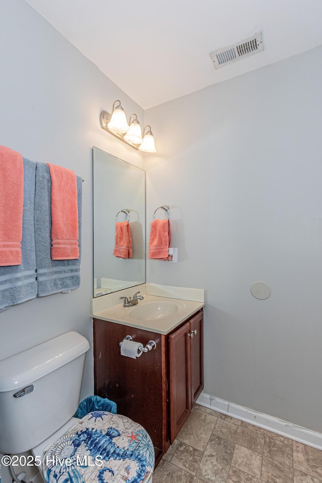 half bath with visible vents, toilet, vanity, and baseboards